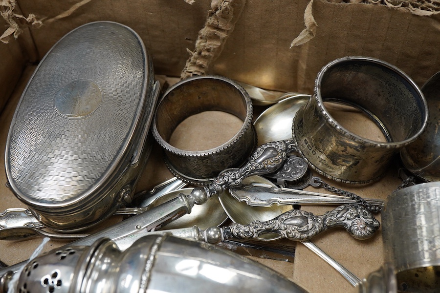 A small collection of silver including a George V mounted oval trinket box, Birmingham, 1916, 95mm, a sugar caster, five assorted napkin rings, five teaspoons, a pair of sugar tongs, handled glove stretchers and button h